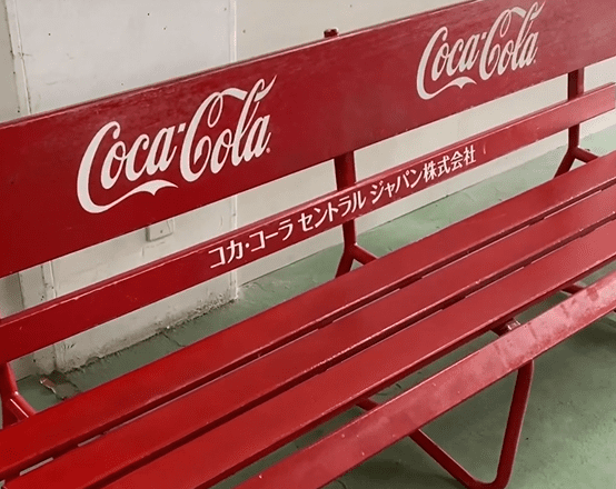 コカ・コーラ セントラルジャパン株式会社の文字が書いた赤いベンチ