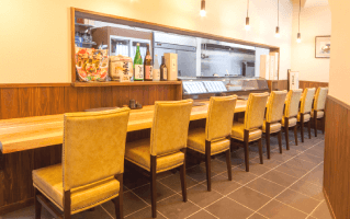 カウンター席が並ぶ飲食店内の様子。奥には厨房が見える。